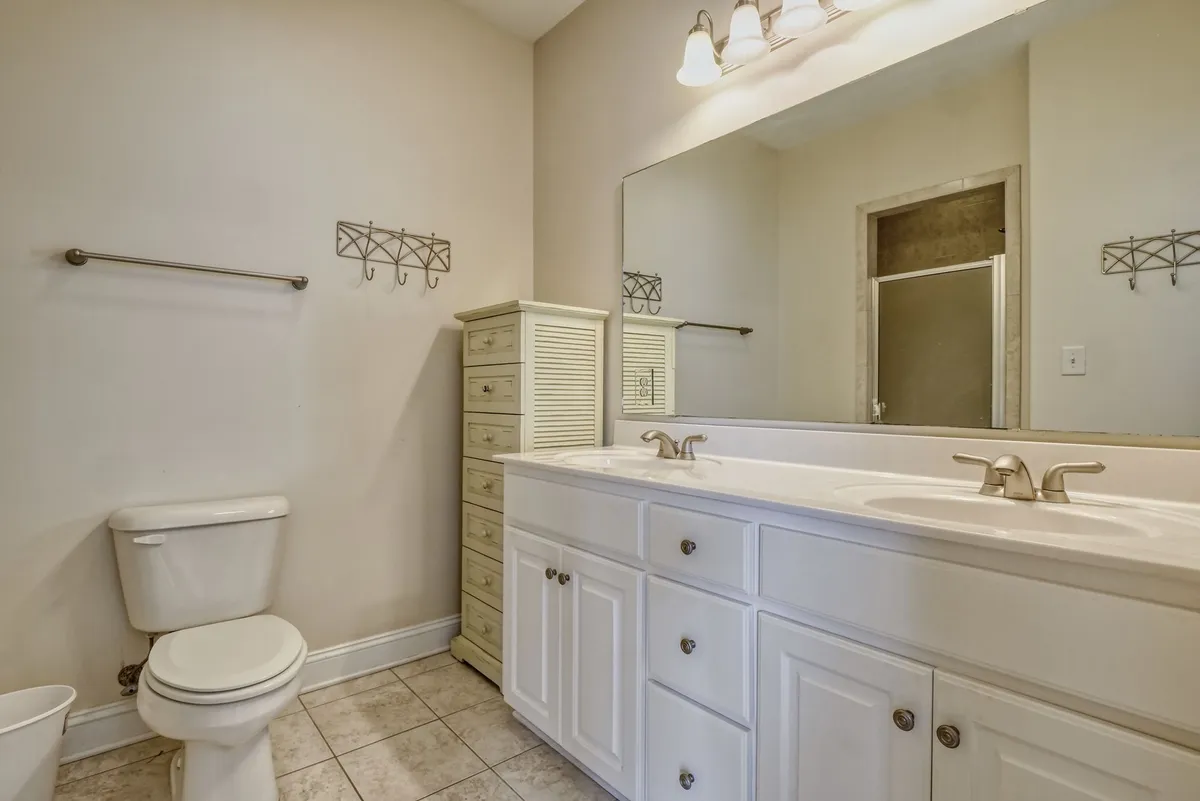 A spa-like bathroom showcasing a double vanity, large mirror, and ample storage. The setting is calm and organized, exuding comfort and modern convenience for morning and evening routines.