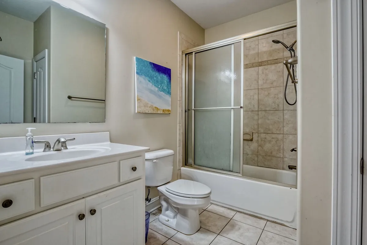 A fresh, bright bathroom scene highlights a walk-in shower, complete with a stylish sink and decorative art. The clean, inviting space is ideal for rinsing off after a swim or a day at the beach, embodying the practical luxury of an outdoor (or adjacent) shower.