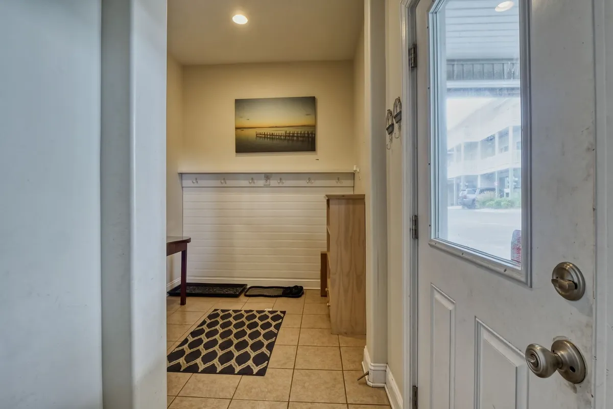 An inviting entryway featuring an entry table, hooks for hanging coats or bags, decorative artwork, and a welcoming doorway. The space is tidy and thoughtfully arranged, emphasizing practical storage and a warm first impression.